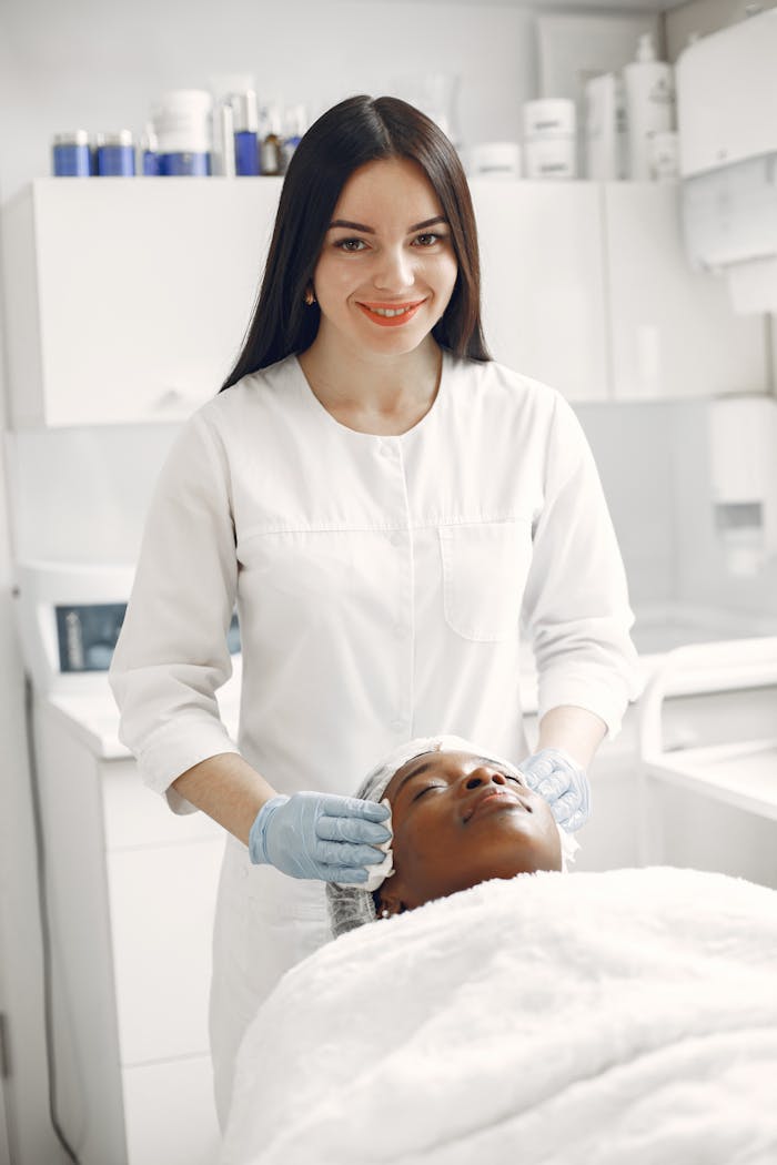 Woman spa professional giving a facial treatment to a client in a serene spa setting.