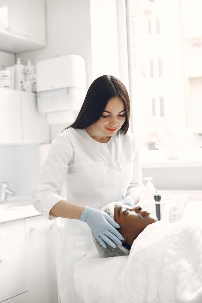 Beautician performing facial treatment on a relaxed woman in a modern spa.